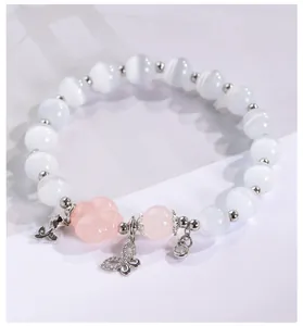 Primer plano de una pulsera de cuentas de ojo de gato con flor rosa y dije de mariposa