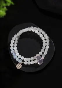 Vista detallada de una pulsera de piedra lunar de dos hilos con cristal de corazón rosa.