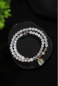 Vista detallada de pulsera de doble hilo de piedra lunar y amatista con colgante de aguamarina.