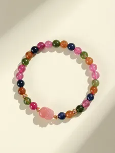 Primer plano de pulsera de turmalina multicolor con dije de Pixiu rosa y cuentas de ágata