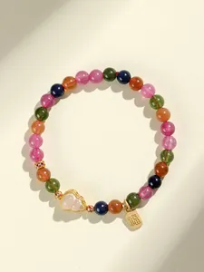 Primer plano de pulsera de cuentas de turmalina de colores con dije de hulu dorado