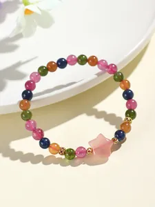 Primer plano de una pulsera de cuentas de colores con dije de estrella rosa en un plato.