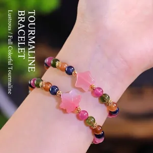 Pulsera de cuentas de turmalina multicolor con dijes de estrella rosa y espaciadores.