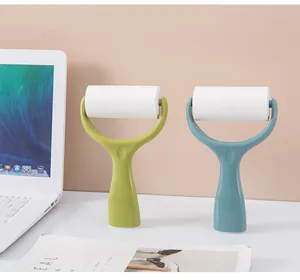 Two vertical lint rollers in green and blue on a clean white desk surface.