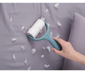 Close-up of a teal blue lint roller removing white hair and lint from purple fabric surface