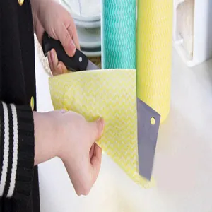 Close-up of yellow wavy non-woven disposable cleaning cloth wiping a large kitchen knife.
