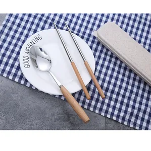 Portable stainless steel cutlery set with wooden handles and storage box on a table