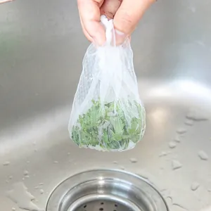 Disposable white mesh kitchen sink filter bag filled with vegetable scraps for anti-clogging.