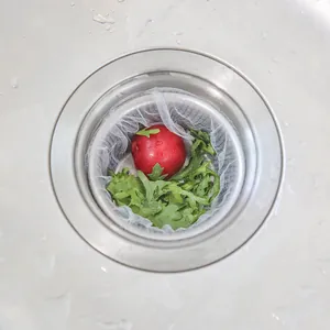 Disposable fine mesh kitchen sink drain filter bag shown installed with food waste scraps