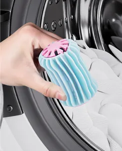Nahaufnahme eines blau-rosa Wäscheballs, der in eine Waschmaschinentrommel gelegt wird