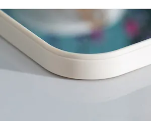 Macro detail of a cream-colored square makeup mirror with rounded corners.
