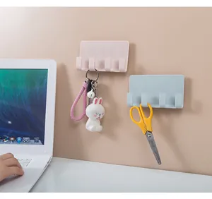 Close-up of pink and blue wall-mounted phone holders with hooks used for keys and scissors.