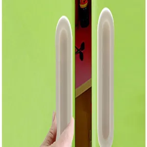 Close-up showing the installation of a white adhesive oval door handle on a window.