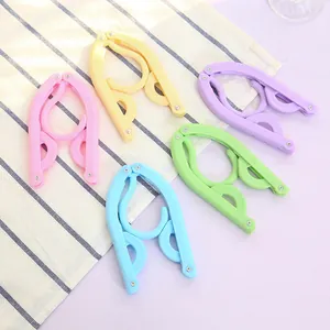 Five colorful portable folding travel hangers displayed on a striped fabric background