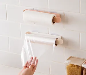 Wall-mounted kitchen organizer rack holding paper towel and plastic wrap on tile wall