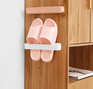 Detail view of wall-mounted slipper rack holding pink slides on a wooden cabinet
