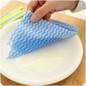 Disposable non-woven cleaning cloth with blue wave pattern used to clean a white plate