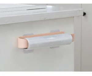 Close-up of the pink adhesive storage rack holding a plastic wrap roll in the kitchen.