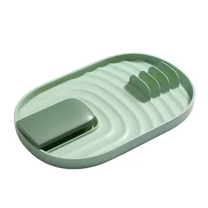 Durable green plastic kitchen utensil rest for spatulas and pot lids on white background