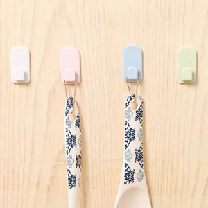 Set of multi-colored self-adhesive wall hooks mounted on a light wood surface