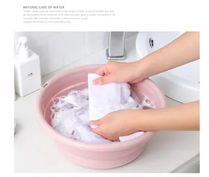 Action shot of washing clothes in a pink collapsible plastic basin for home use
