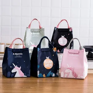 Insulated lunch bags in various colors with unicorn and summer prints on wooden table