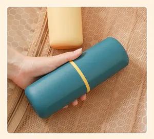 Detailed view of a hand holding a portable teal travel toothbrush and toothpaste storage case