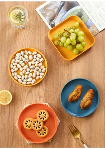 Detailed view of colorful plastic snack plates with assorted food on wooden table.