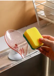 Detalle de jabonera en forma de hoja con ventosa y drenaje para guardar esponjas de baño.