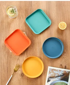 Top view of colorful square and round plastic snack plates on wooden background