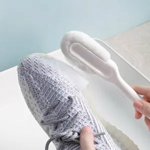 Soft bristle shoe brush cleaning white knit sneaker for home use.