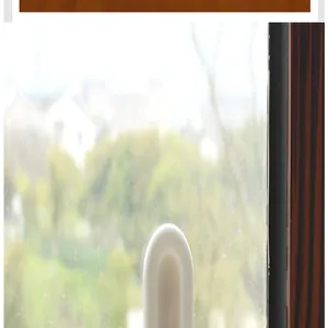 Detailed view of a white self-adhesive auxiliary handle installed on a glass window pane