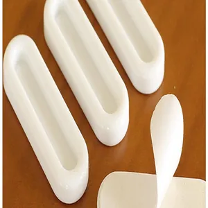 Close-up of self-adhesive white oval handles showing the peel-and-stick backing.