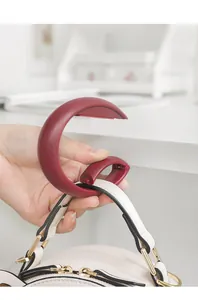 Close-up of portable burgundy table-side hook hanging a white bag on desk edge