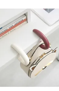 Portable desk-side bag hook set in white and red shown holding a stylish cat-shaped purse