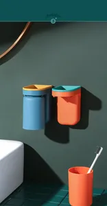Close-up of wall-mounted orange and blue toothbrush holders in a modern bathroom