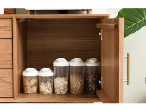 Nahaufnahme von transparenten Vorratsgläsern mit weißen Deckeln in einem Schrank aus Naturholz.