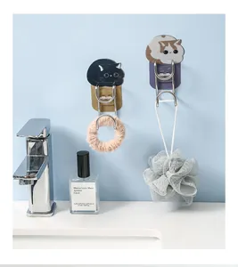 Detail of cute cat-shaped stainless steel wall hooks holding a loofah and hair tie