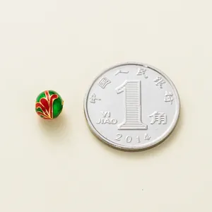 Detailed macro view of 6mm green and red enamel gold-plated silver bead with scale coin