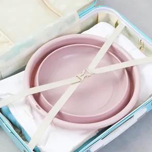 Portable pink collapsible washbasin stored inside a travel suitcase with clothes