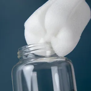 Close-up of a white sponge cleaning brush used for washing a tall glass water bottle