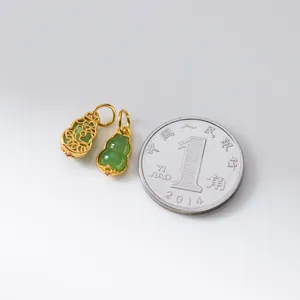 Macro view of tiny S925 silver Hetian jade gourd pendants next to a coin for size