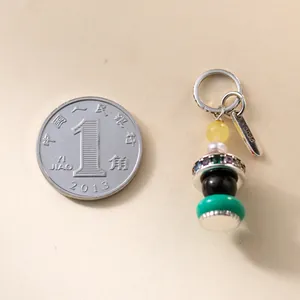 Dettaglio macro che mostra un ciondolo in argento S925 con perle colorate e perla