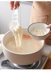 Action d'un serveur de nouilles blanc soulevant des spaghettis d'une casserole vers un bol en céramique