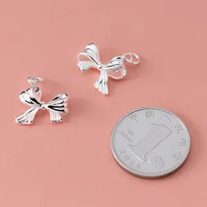 Detailed close-up of 925 sterling silver bow-knot charms for DIY jewelry bracelet making