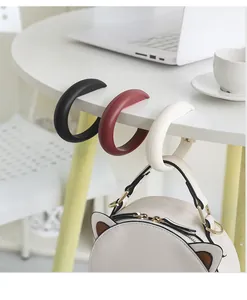 Portable bag hooks clipped to desk edge holding a backpack in a study setting