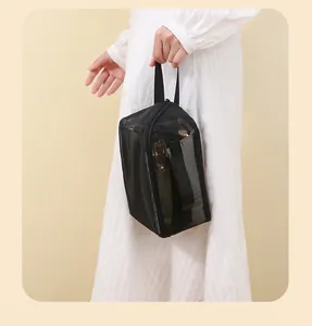 Detail view of a portable black mesh cosmetic bag being carried by hand for travel use
