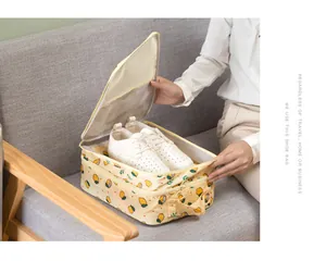 Detailed view of an open lemon print oxford cloth shoe storage bag with white shoes