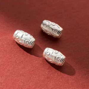 Three 10mm dZi style silver spacer beads with vintage patterns on red background