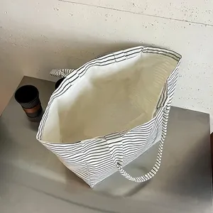Vista detallada que muestra el interior espacioso de un bolso tote de lona a rayas